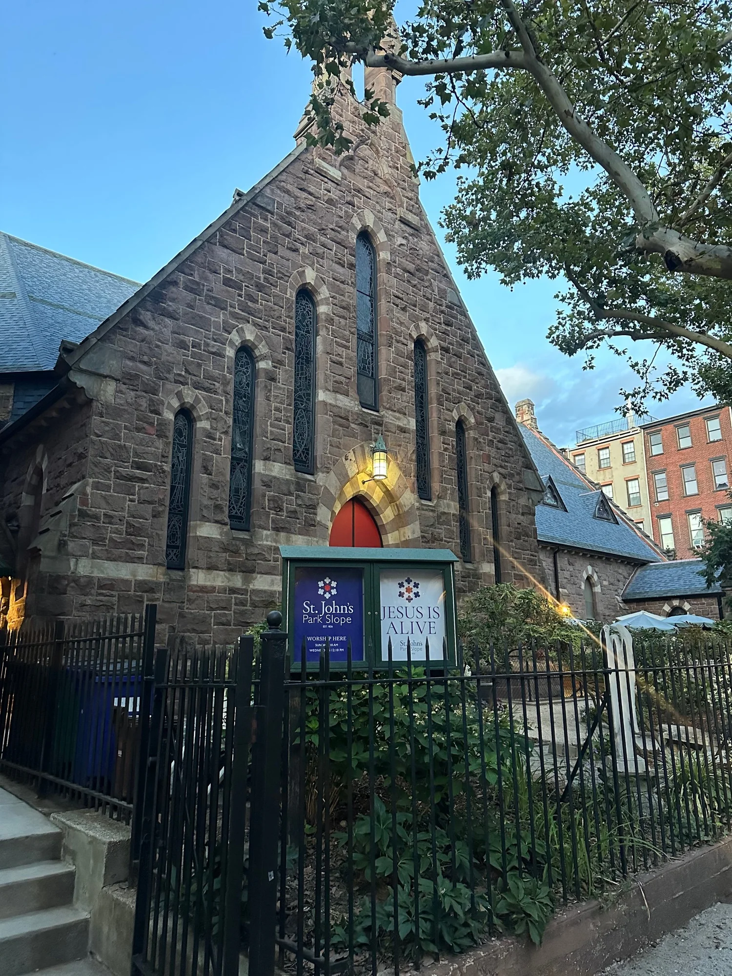 St. John's brownstone church at dusk on St. Johns Place, the lantern lit over the red door