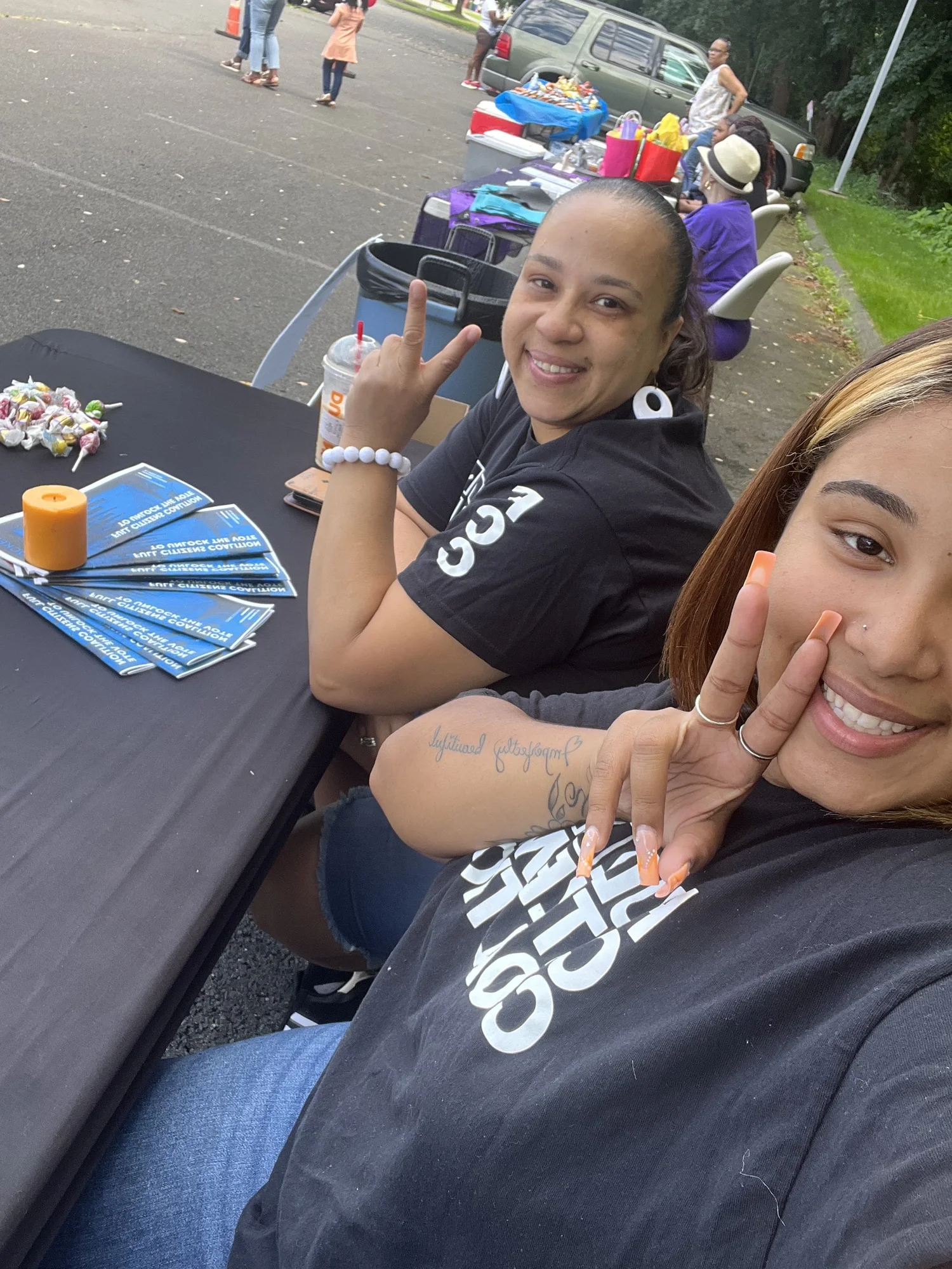 Two women at a table covered in Unlock the Vote guides