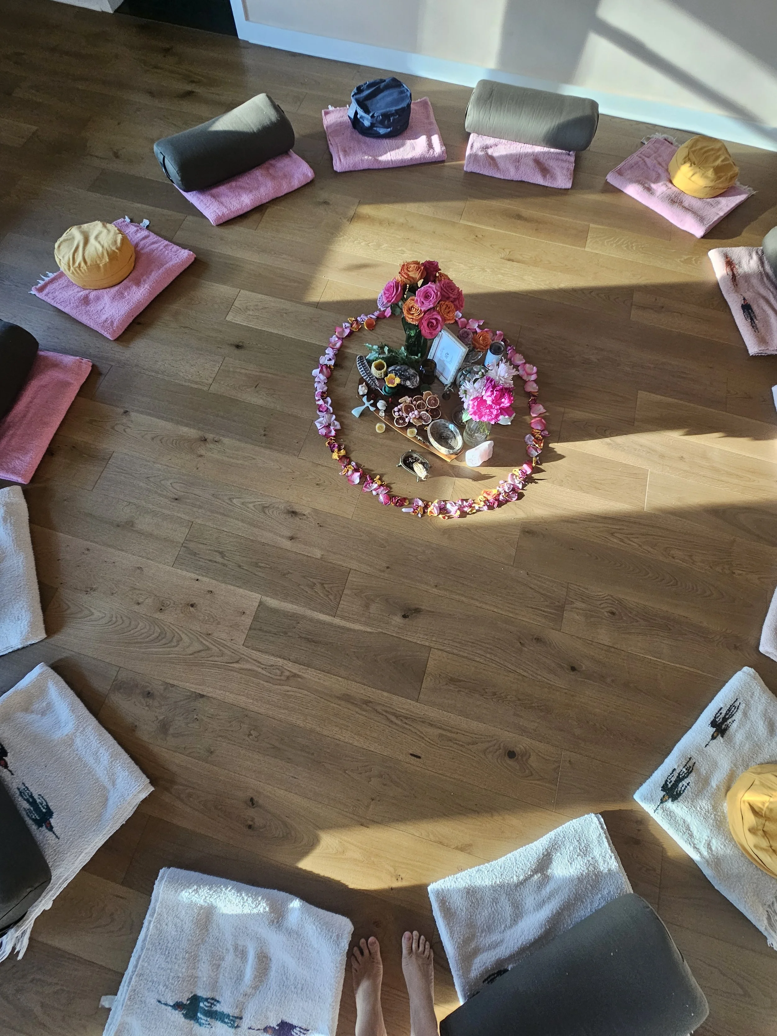 A circle of cushions around a center altar of rose petals in the Sanctuary Room