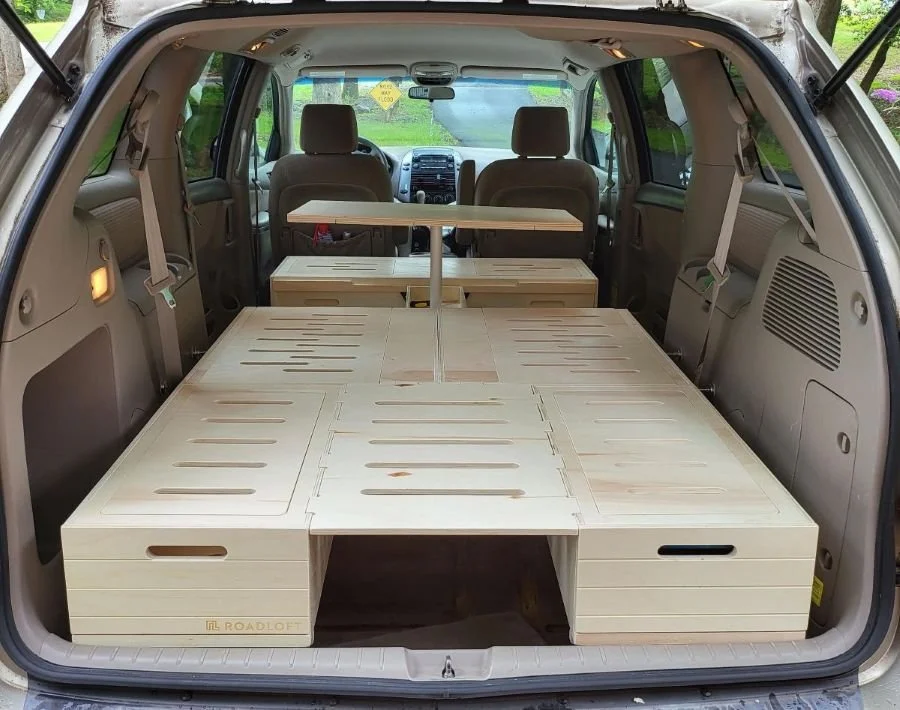 Roadloft minivan conversion kit fully installed in a 2006 Toyota Sienna, bed platform and table visible