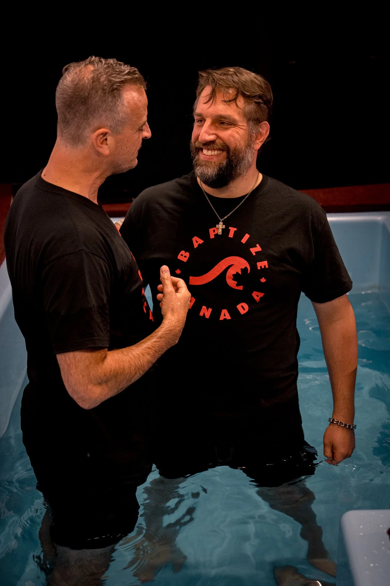 A pastor prays with a man in the baptism tank at Journey Church Calgary