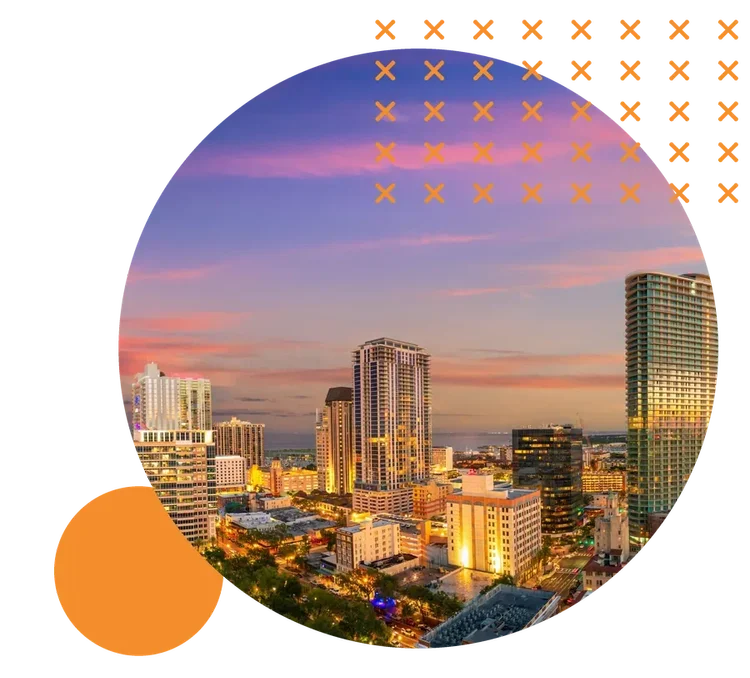 The downtown St. Petersburg skyline under a pink and purple sunset, with Tampa Bay in the distance
