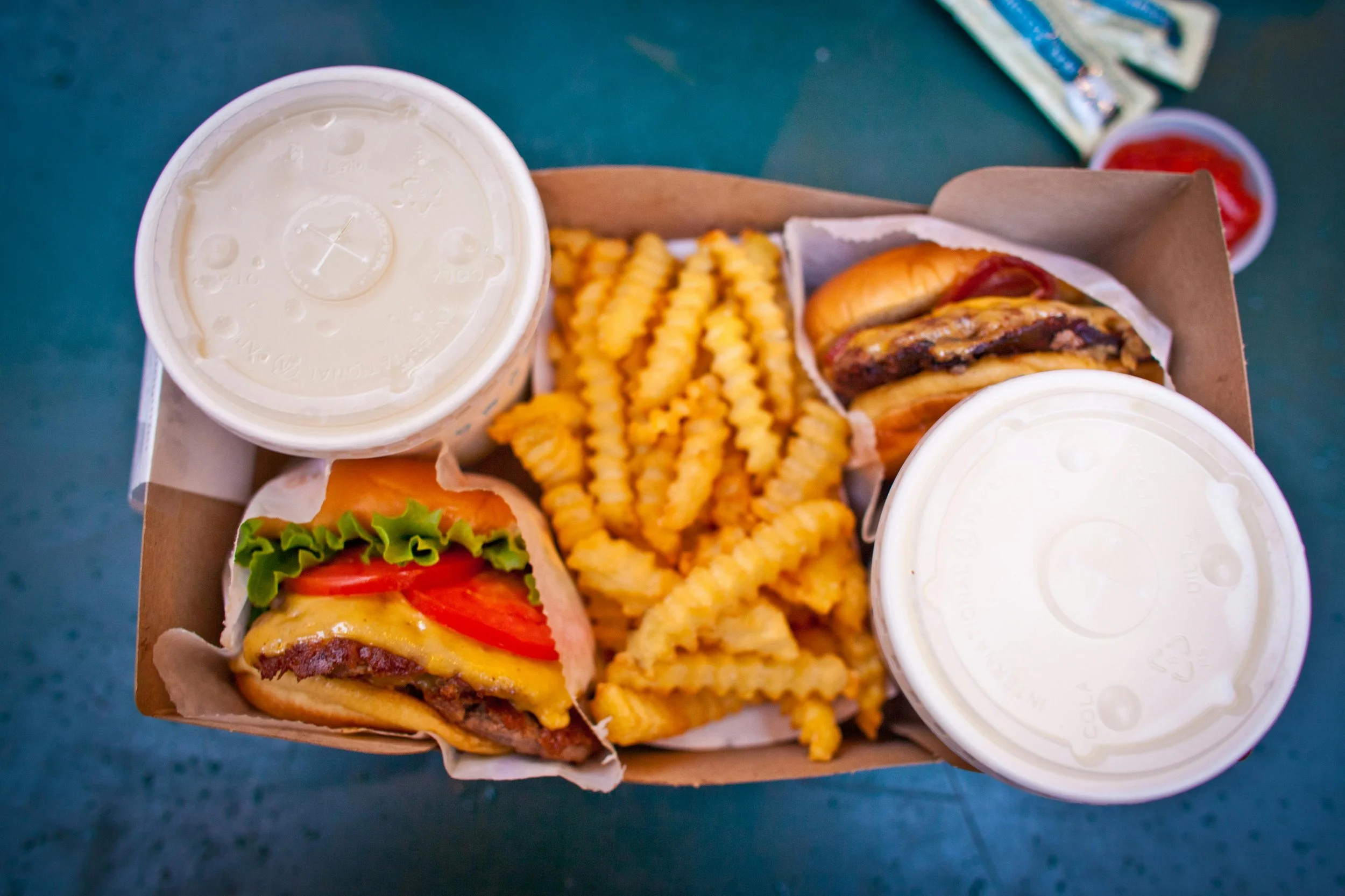 Cheeseburger, fries, and soft drink in to-go containers.