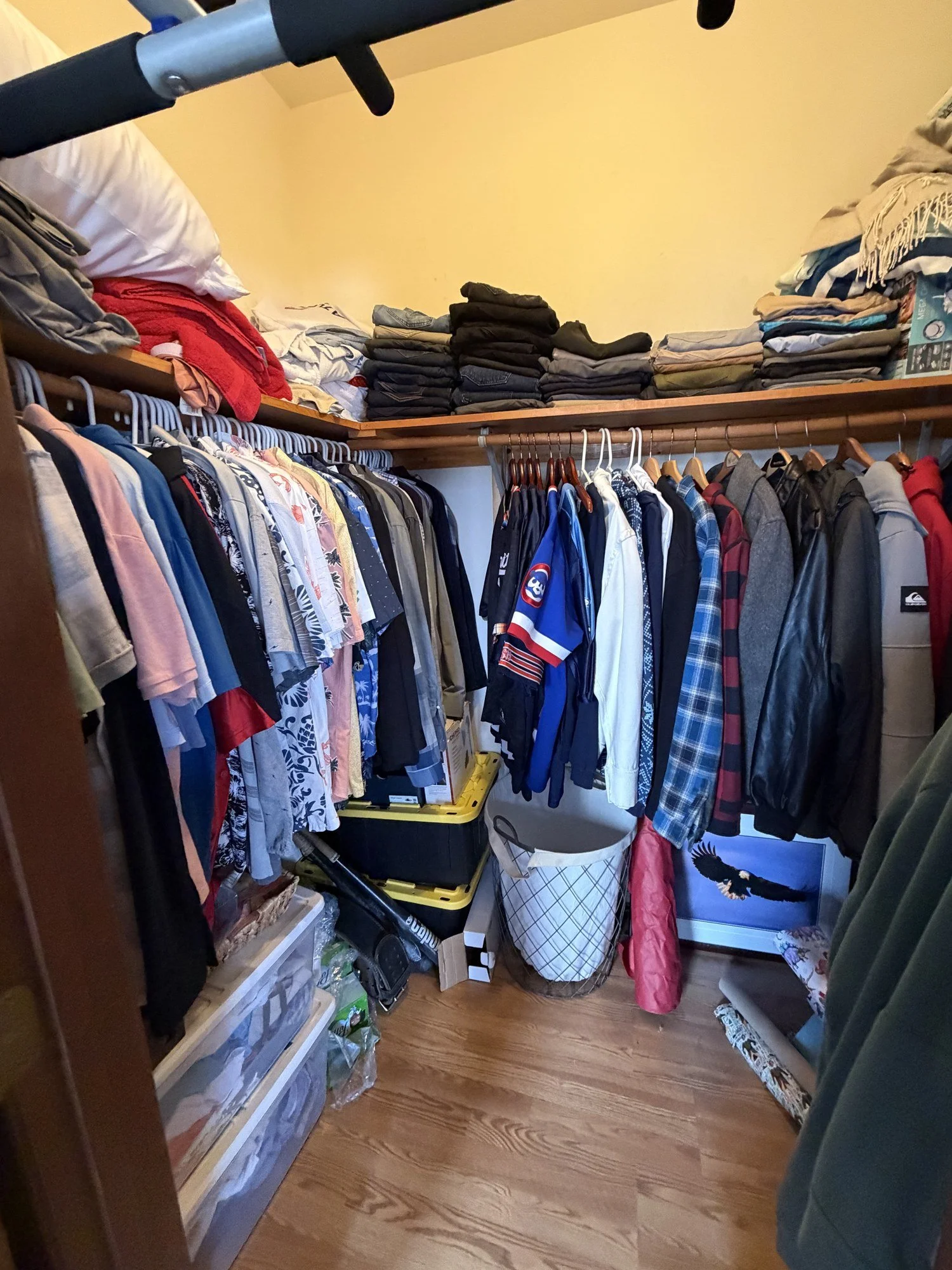The same closet after the audit, with neatly folded stacks on the upper shelf and organized hanging garments