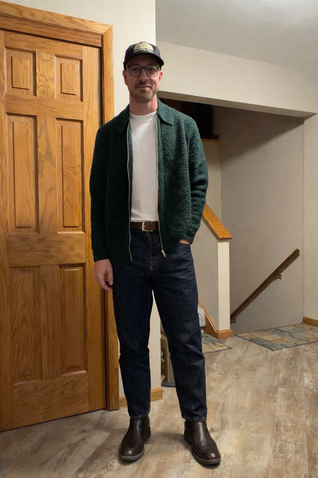 Green textured jacket with dark denim and brown boots