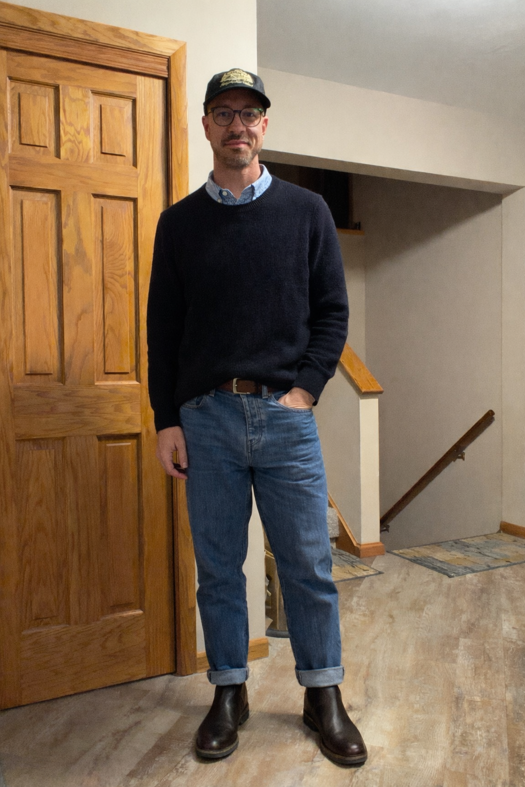Navy knit over a blue shirt with cuffed jeans and boots