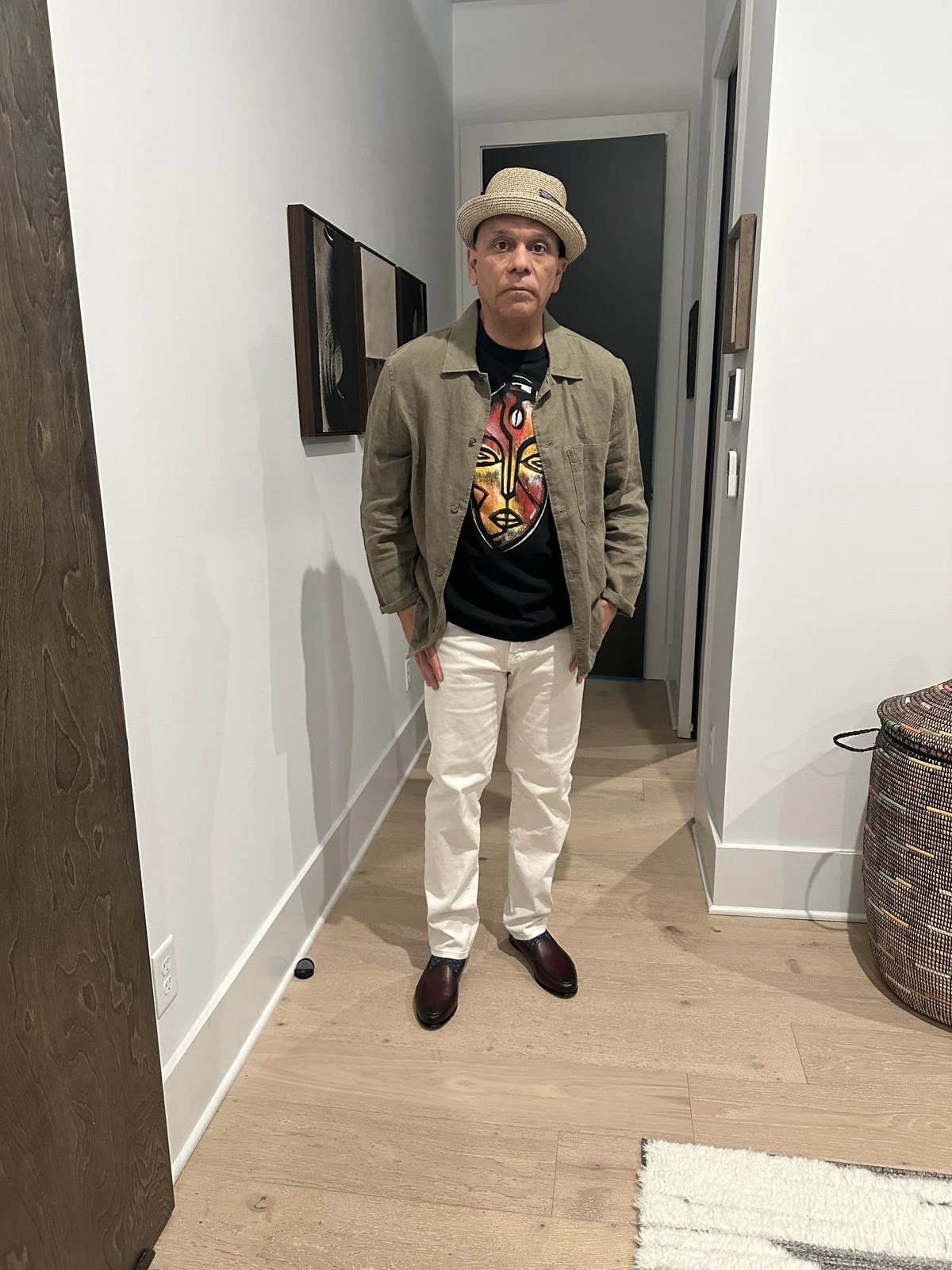 Tan jacket and graphic tee styled with cream trousers and a hat