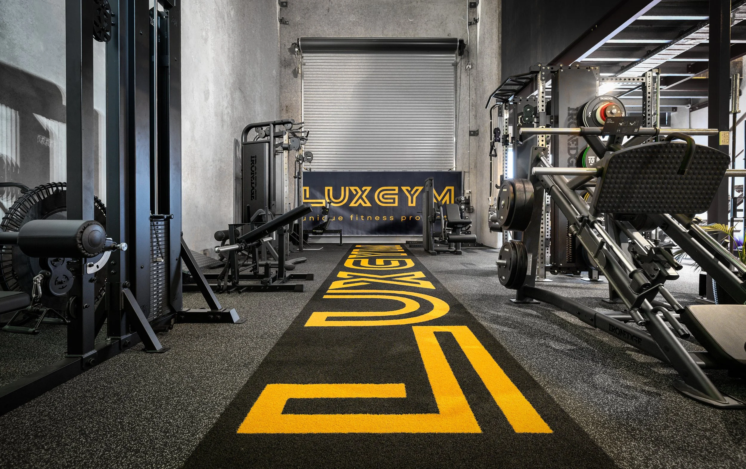 The LUXGYM performance showroom in Cooroy with a turf runway carrying the LUXGYM logo between Ironedge machines and racks