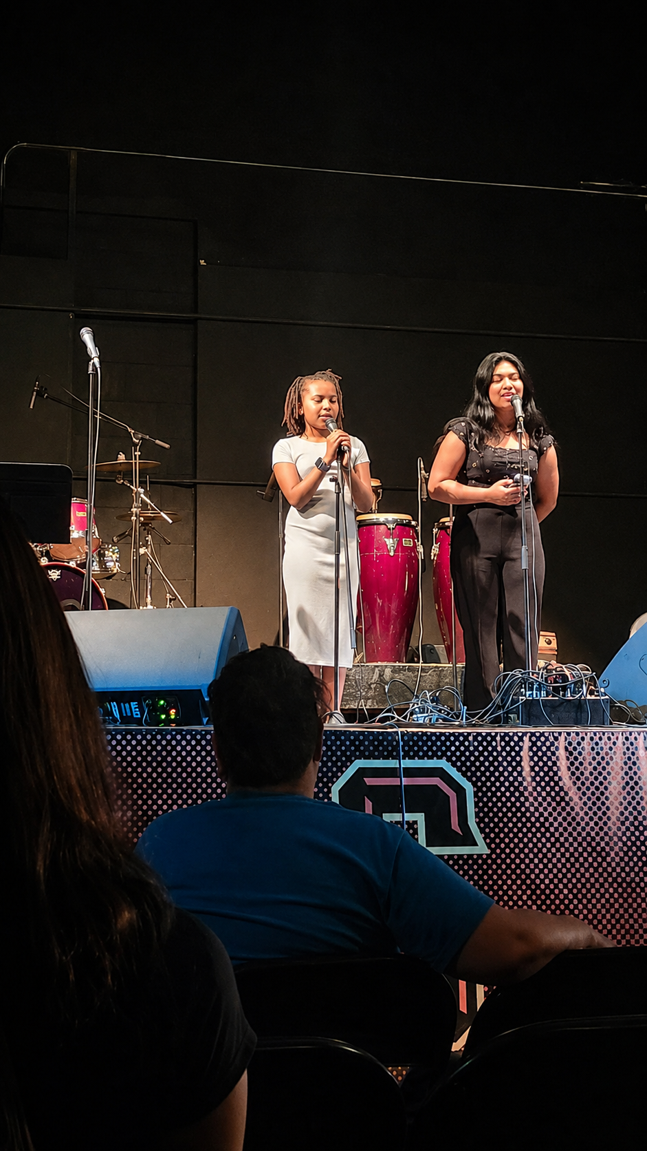 Two young women singing on stage during a Club performance