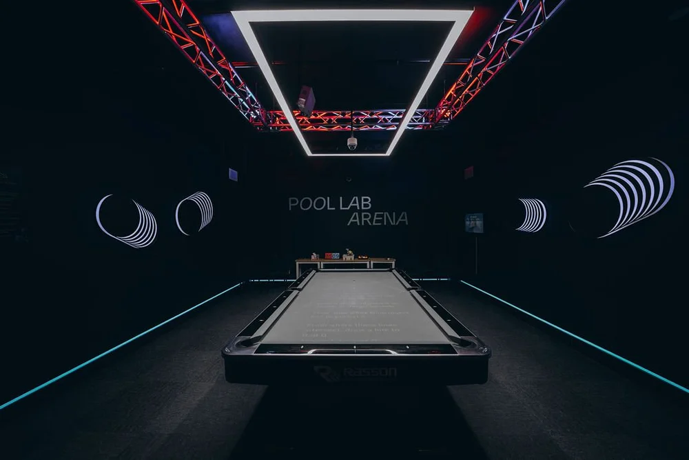 Pool Lab Arena: Rasson 9ft table with a billiards training drill projected on the cloth under a Predator LED light, for PRO members and Residents