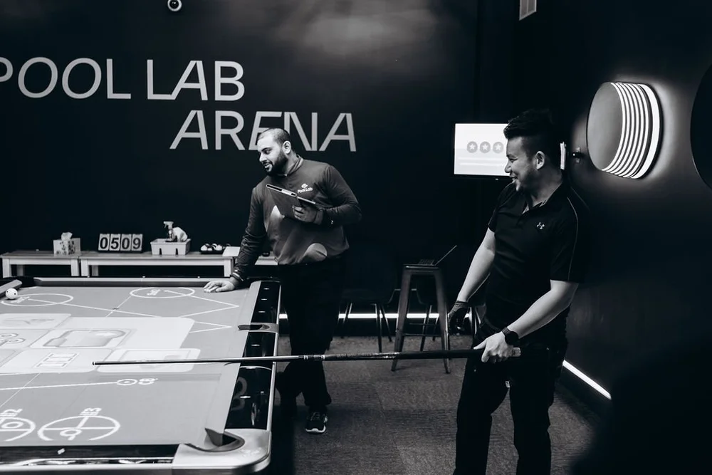 Instructor demonstrates how to use the drill projector on the Rasson 9ft Arena table during a billiards lesson at Pool Lab