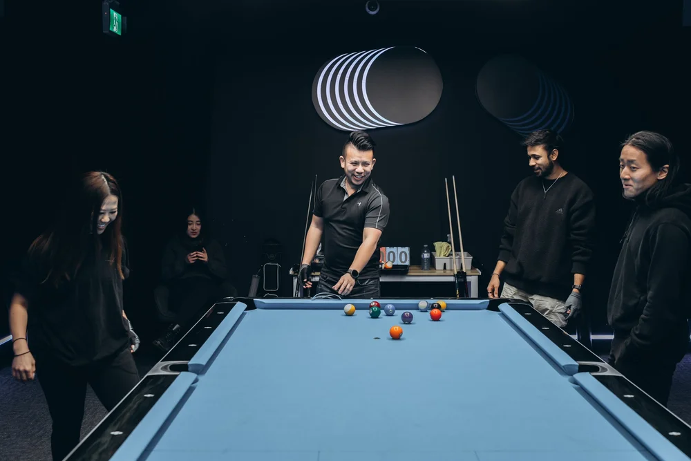 Friends playing pool on a Rasson 9ft table with Simonis 860HR tournament blue cloth in a private billiards room at Pool Lab Etobicoke