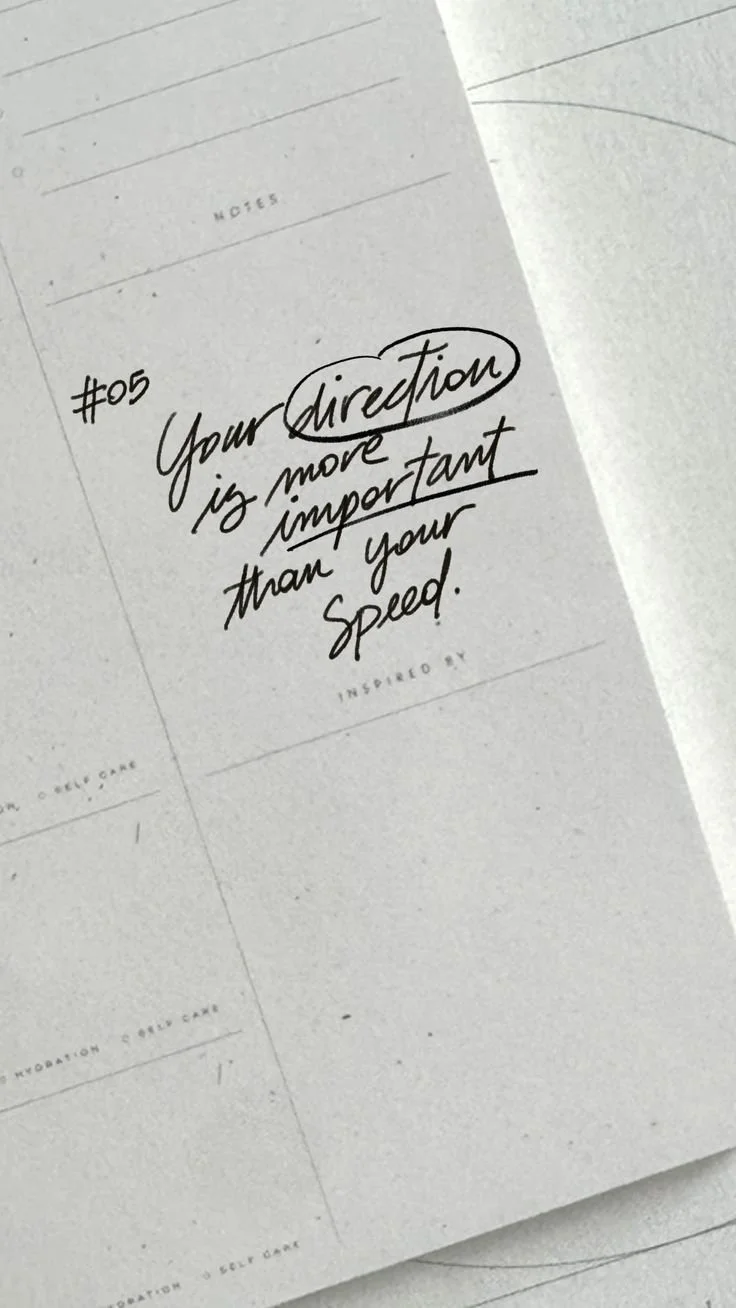 An open notebook with the handwritten words: Your direction is more important than your speed