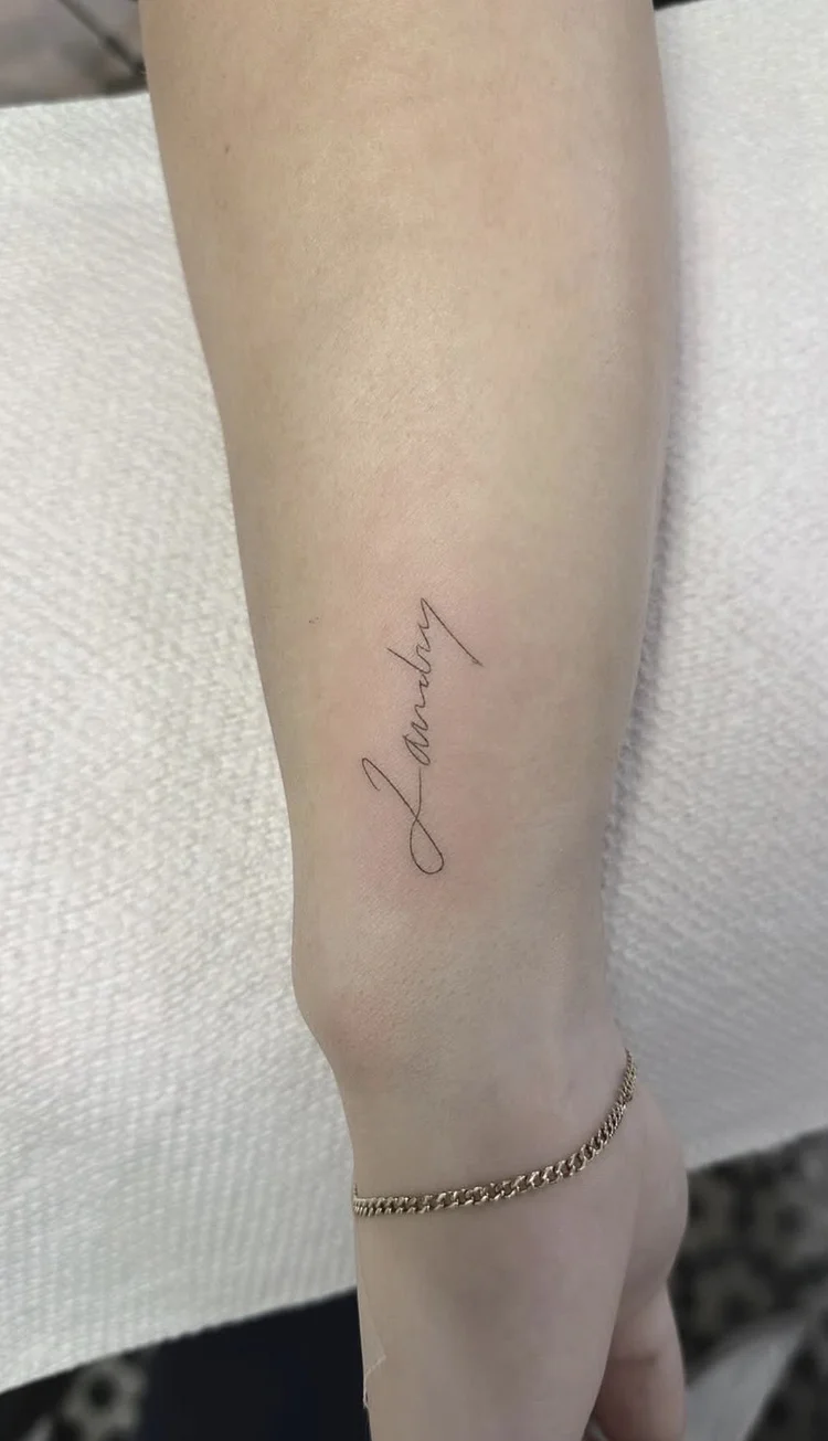 Vertical Name Script fine-line tattoo