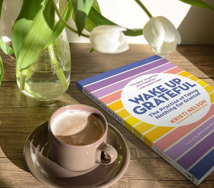 Bedside table with Wake Up Grateful book, tulips, and cup of coffee