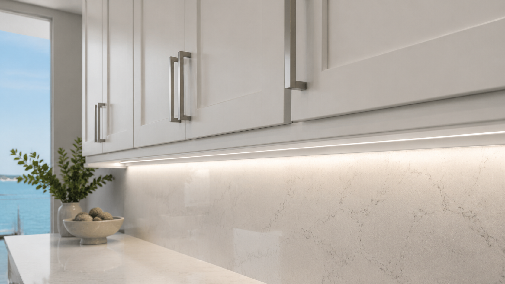 Cool-white full-overlay Shaker wall cabinets with precisely fitted light-rail moulding concealing continuous under-cabinet LED lighting