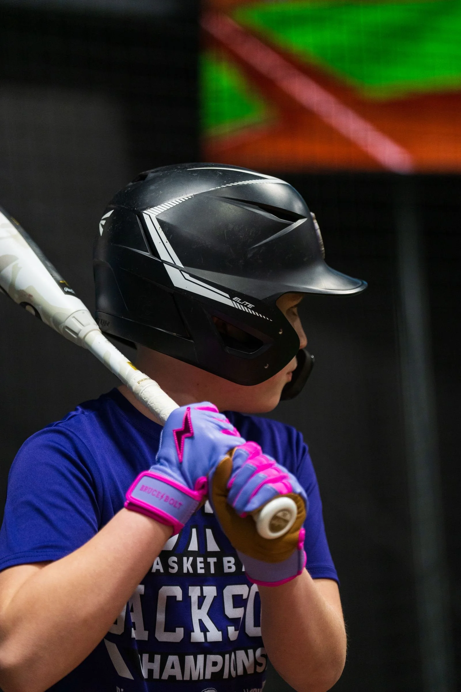 Velocity Sports athlete in batting stance with HitTrax stadium graphics on the screen behind
