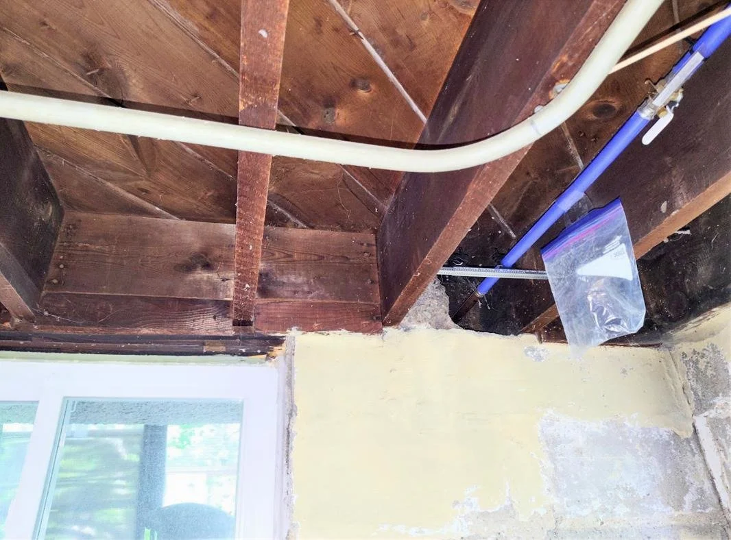 Basement and floor framing area showing an opening near the exterior wall, suggesting a lower-boundary issue to verify before final scope