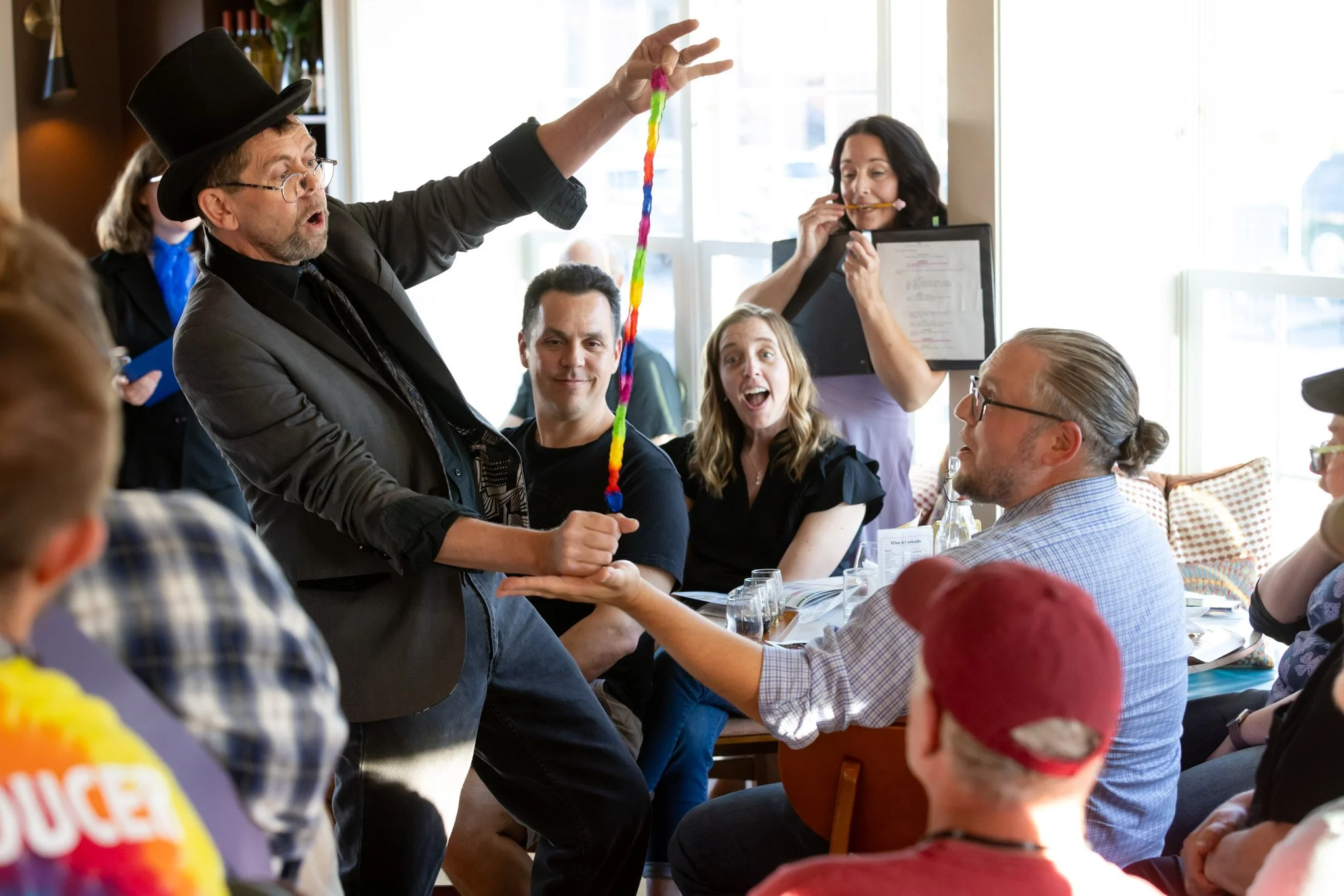A small stage performance by a man with a top hat in front of an engaged audience
