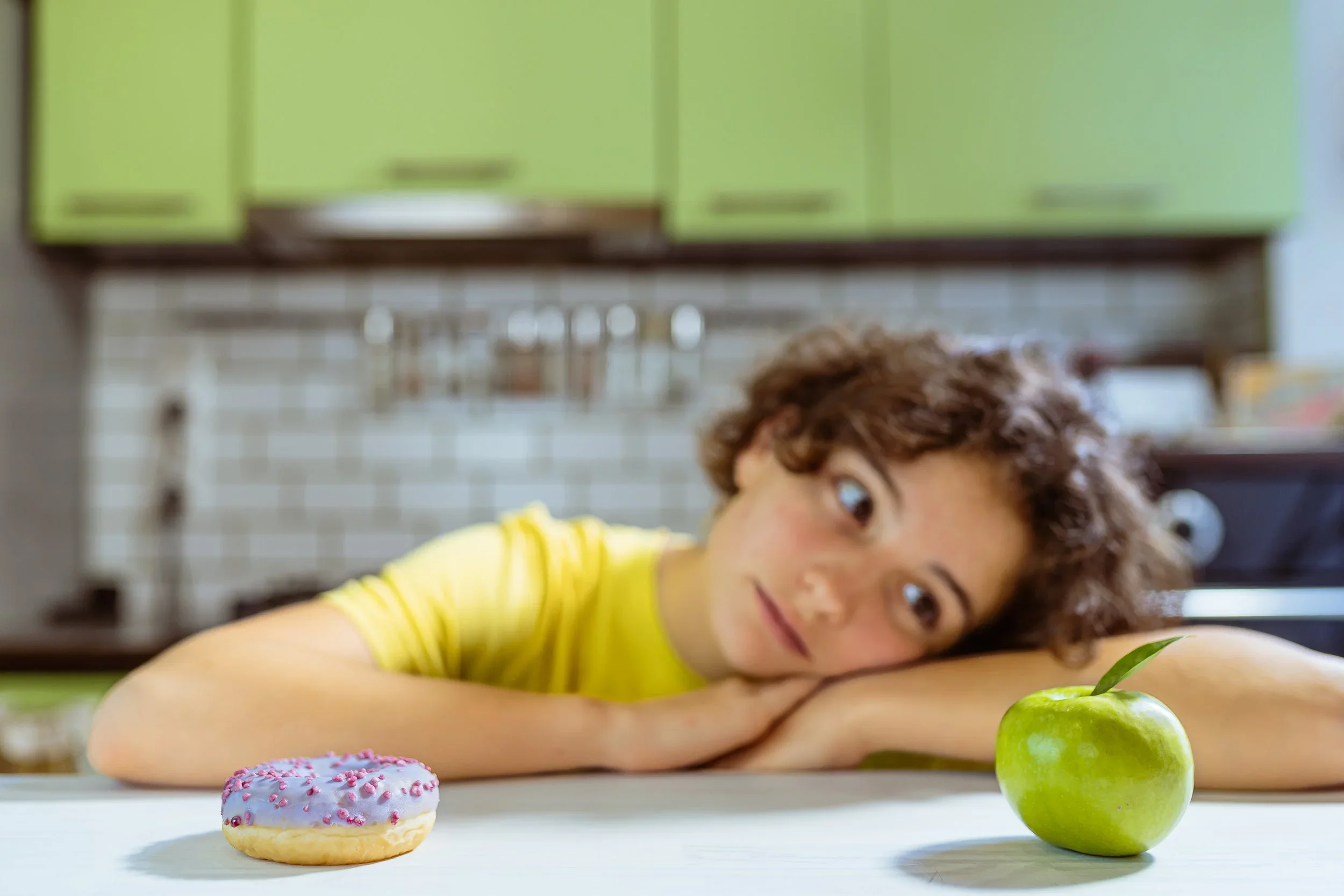 Child considering a doughnut and an apple while managing food choices