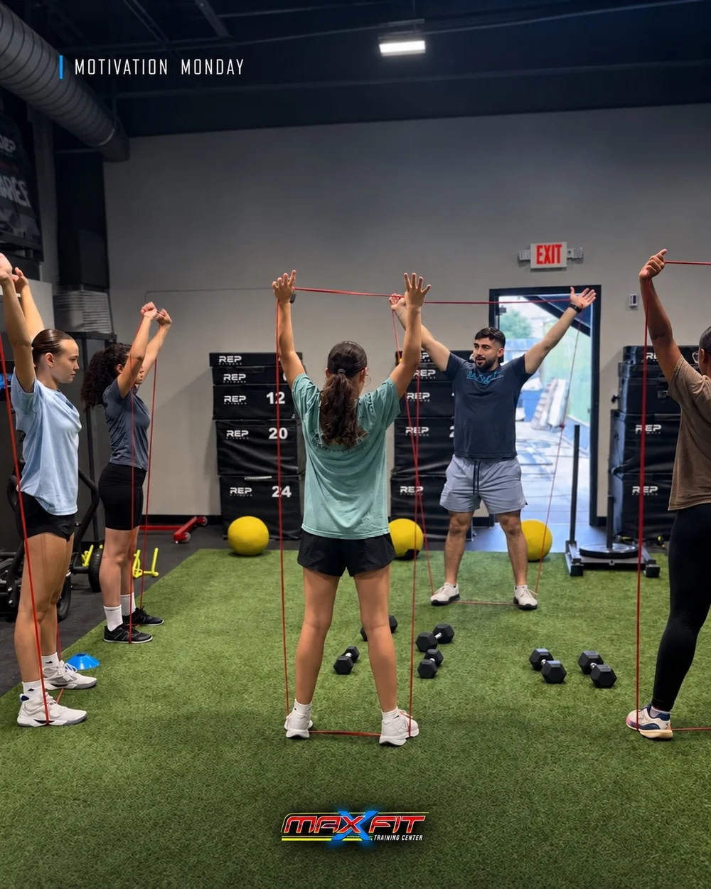 Coach leading a resistance-band warm-up on the turf