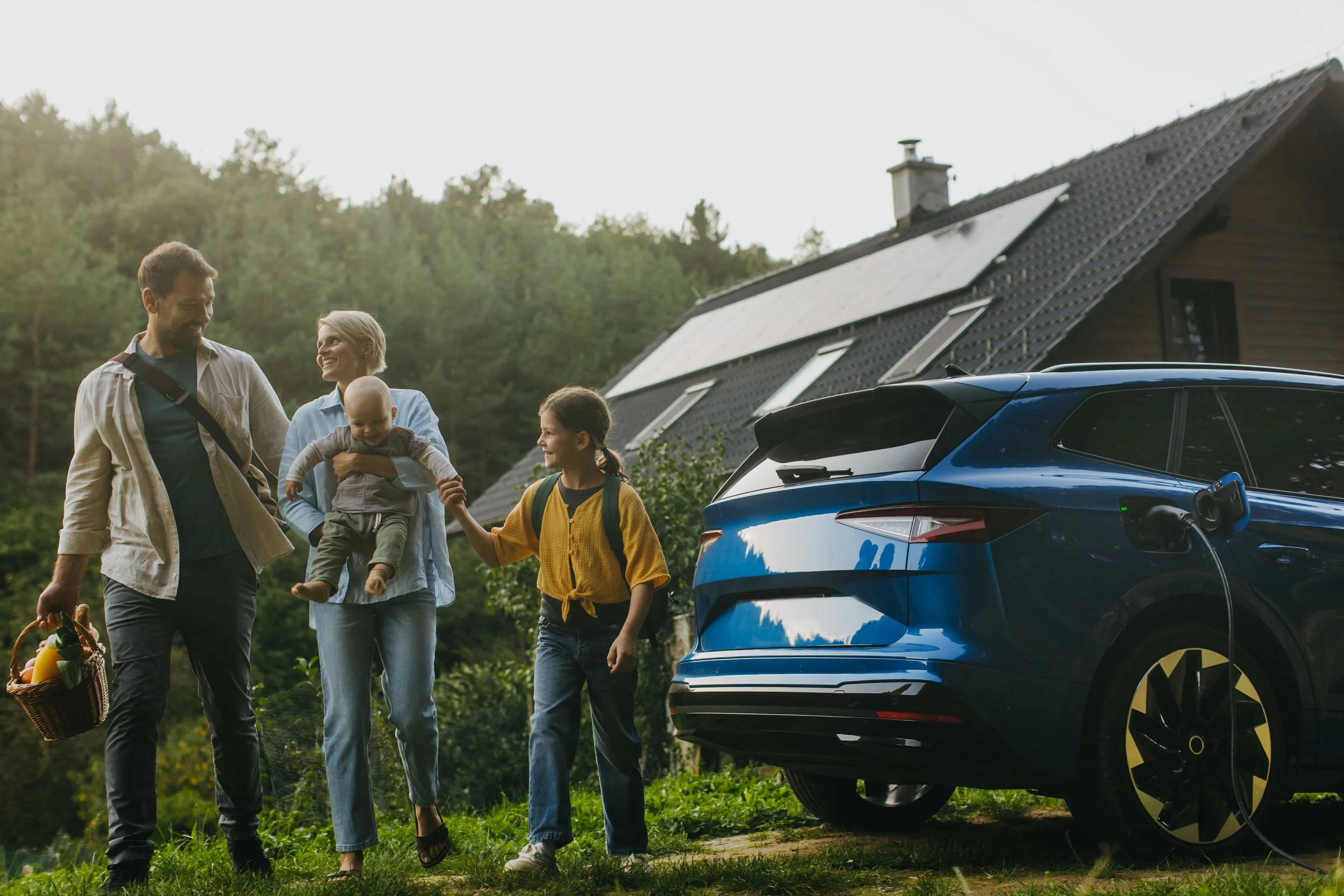 Electric vehicle charging beside a home with rooftop solar panels