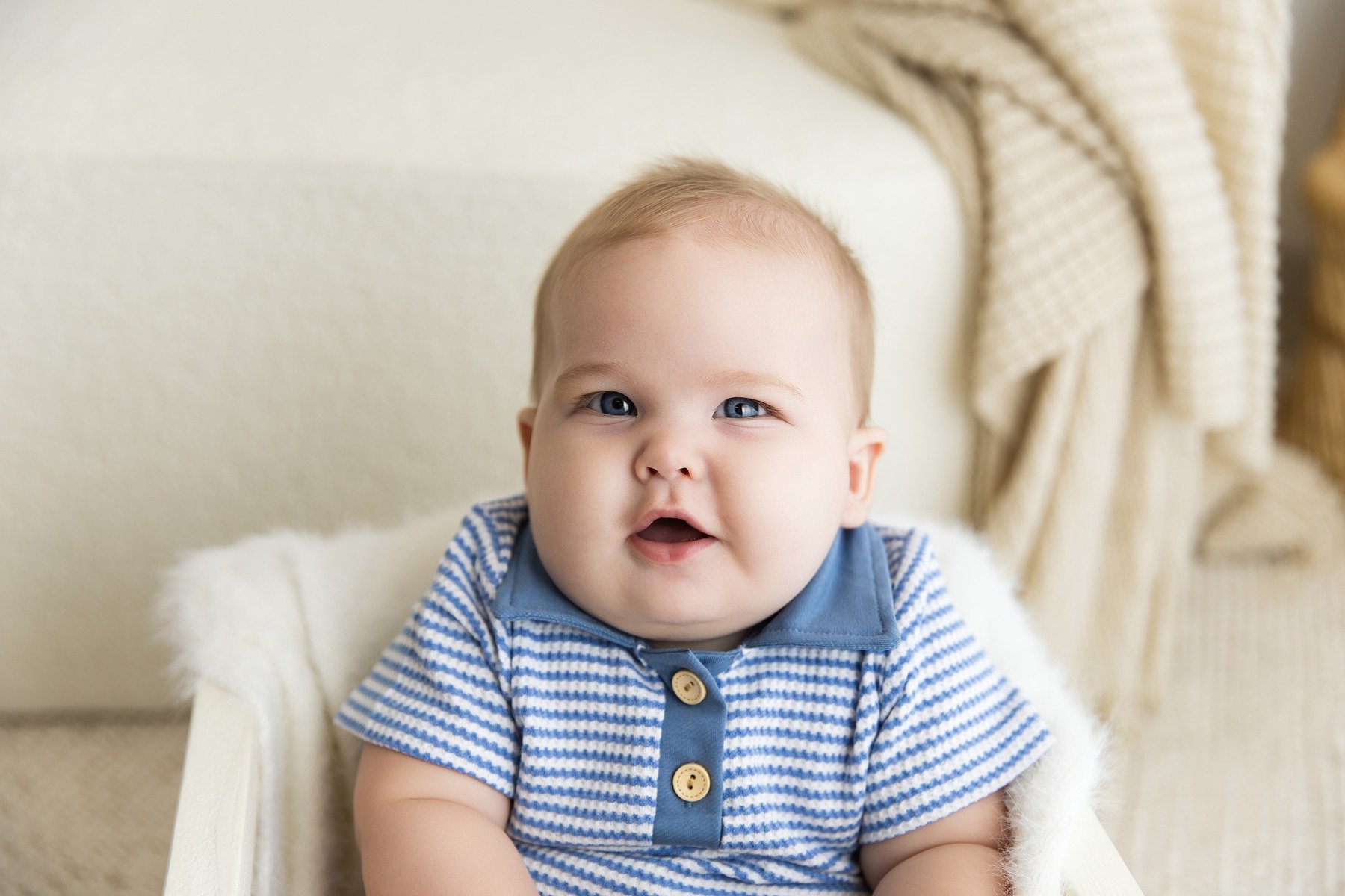 Six-month-old Paxton smiling in a blue striped outfit