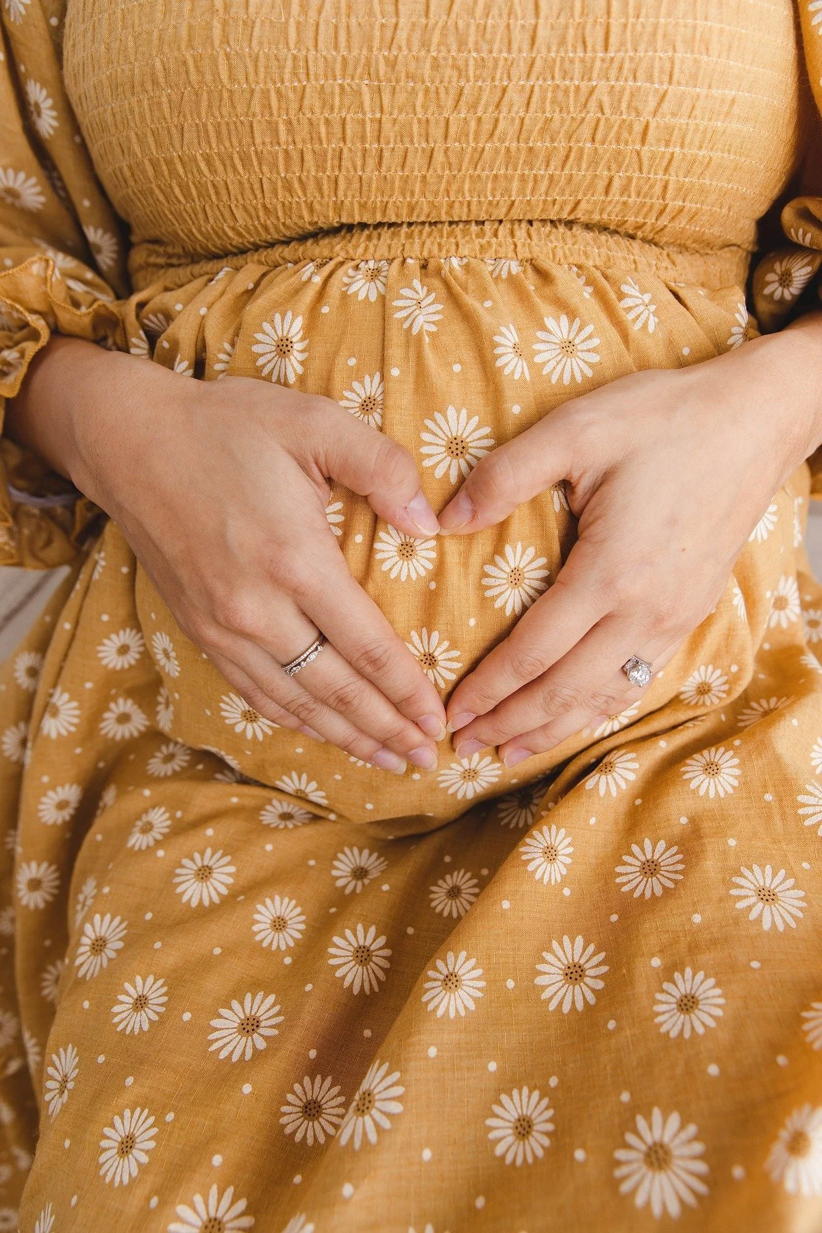 Lifestyle maternity photography in Allen, Texas: baby bump detail in a soft neutral studio, photographed by Manal Ansari