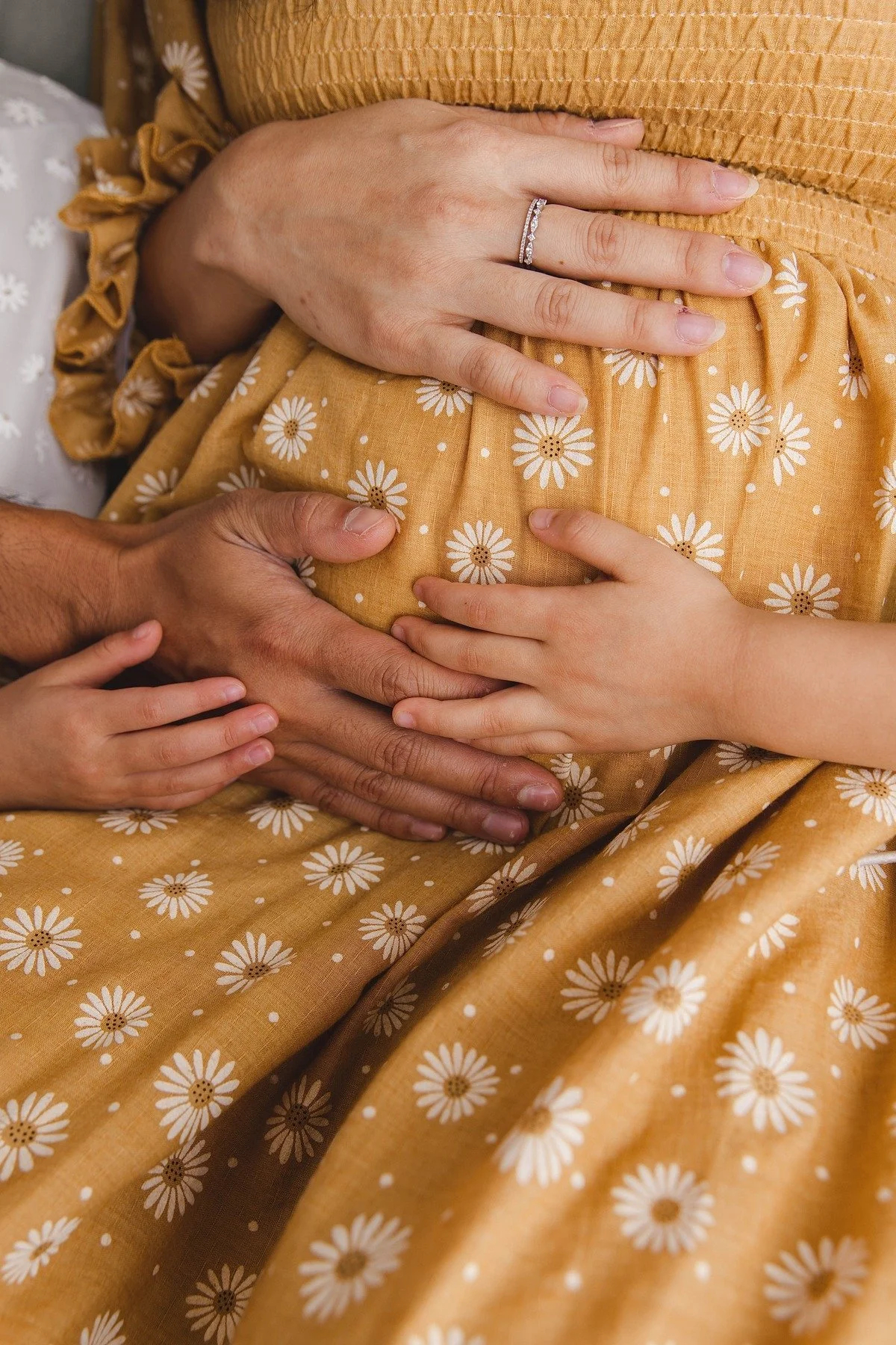 Family hands resting gently on a baby bump during an Allen maternity session