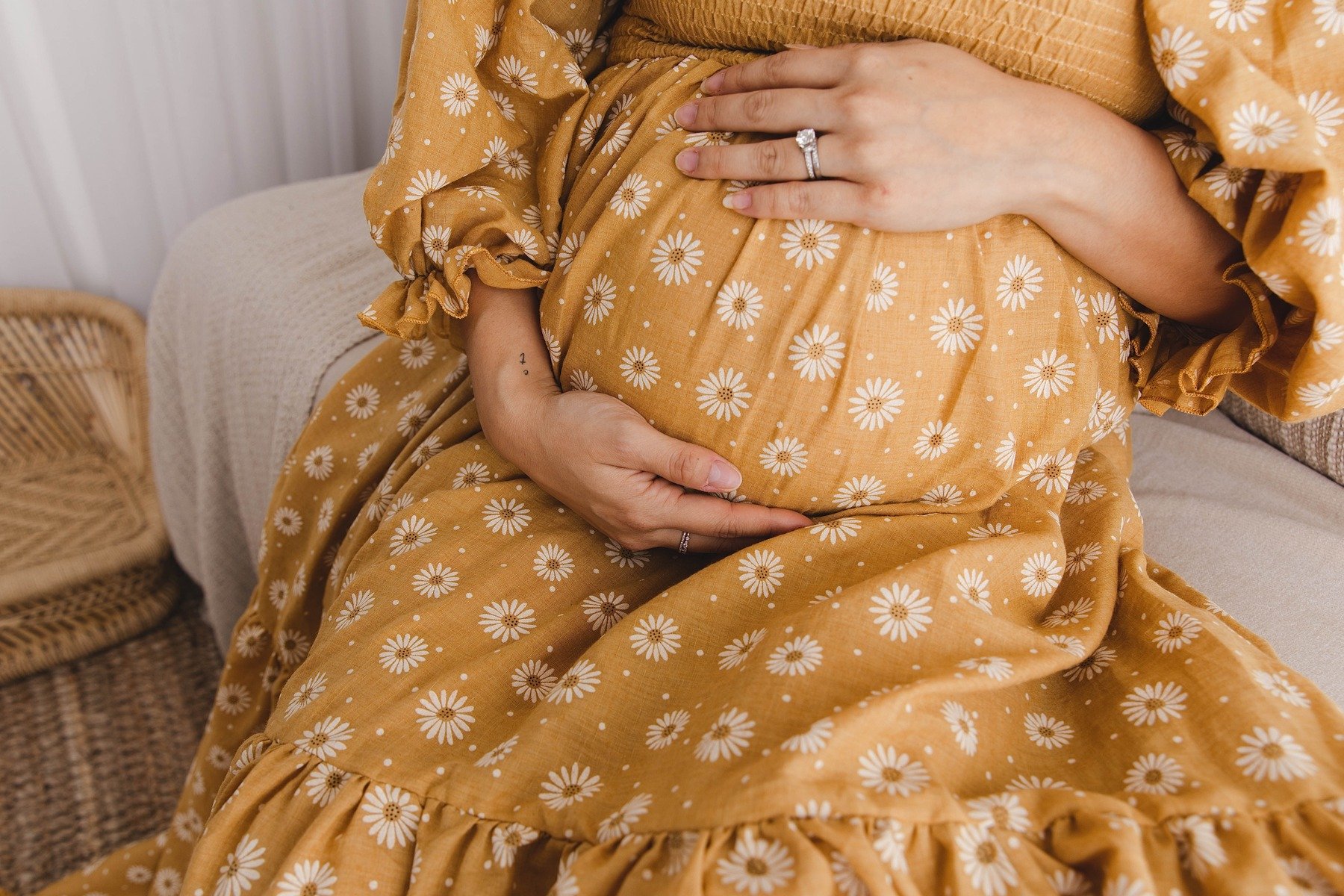 Lifestyle maternity photography in Allen, Texas: baby bump detail in a soft neutral studio, photographed by Manal Ansari