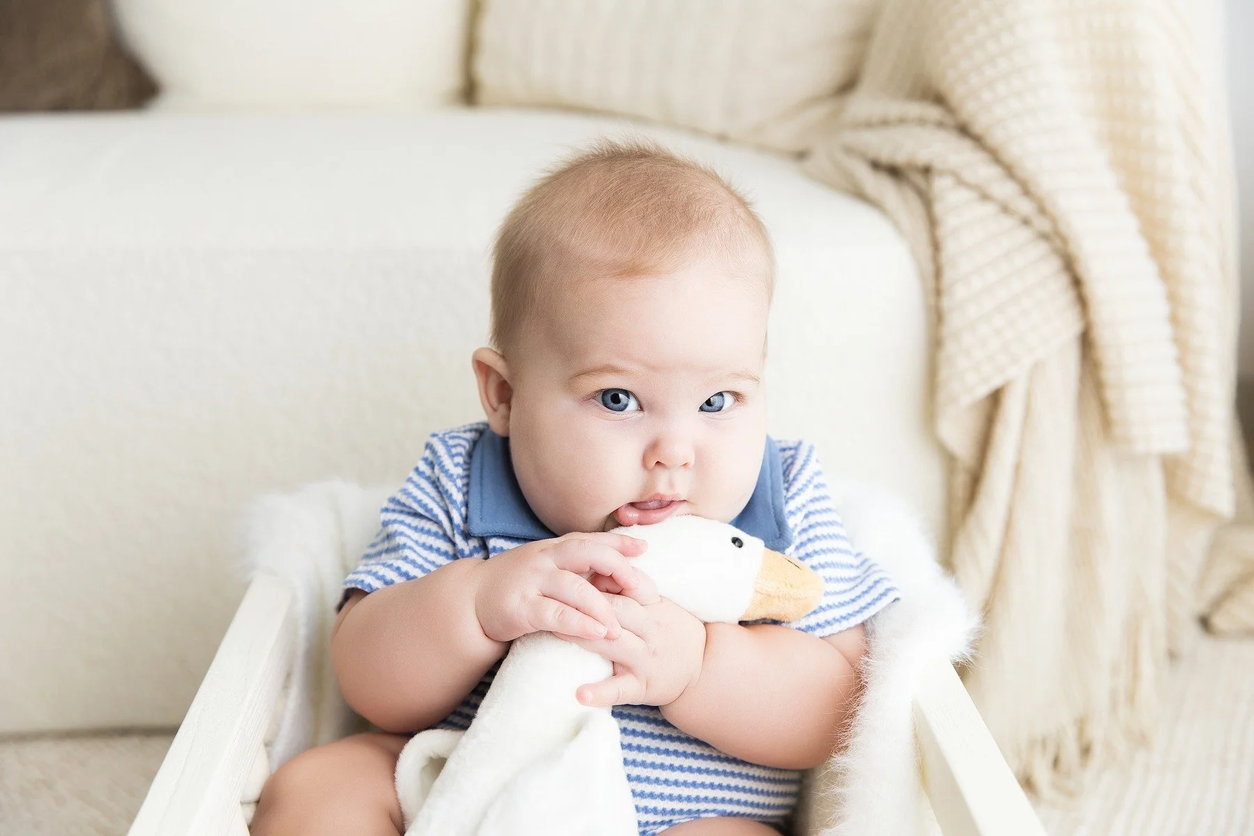 Paxton in a blue striped outfit with a soft white blanket