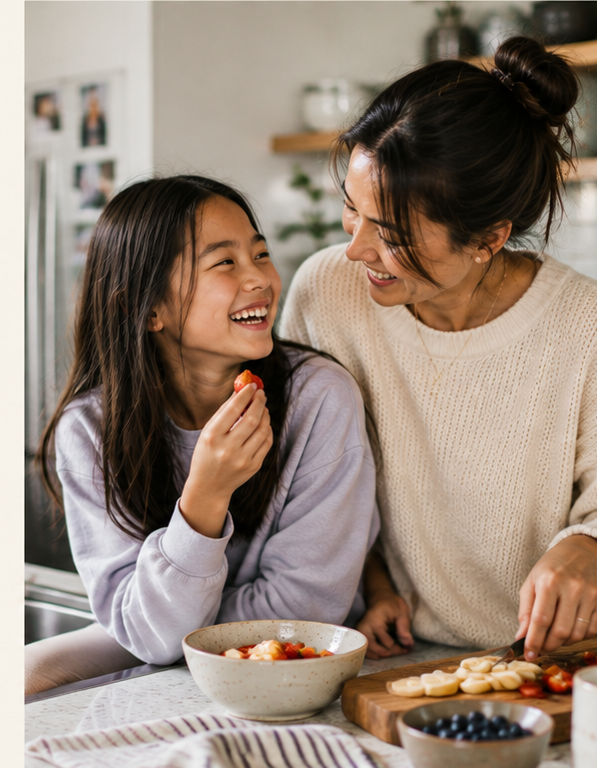 A mother and daughter laughing together while preparing food in the kitchen, sharing a moment of connection.