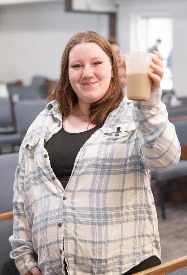 A woman raising her coffee cup and smiling