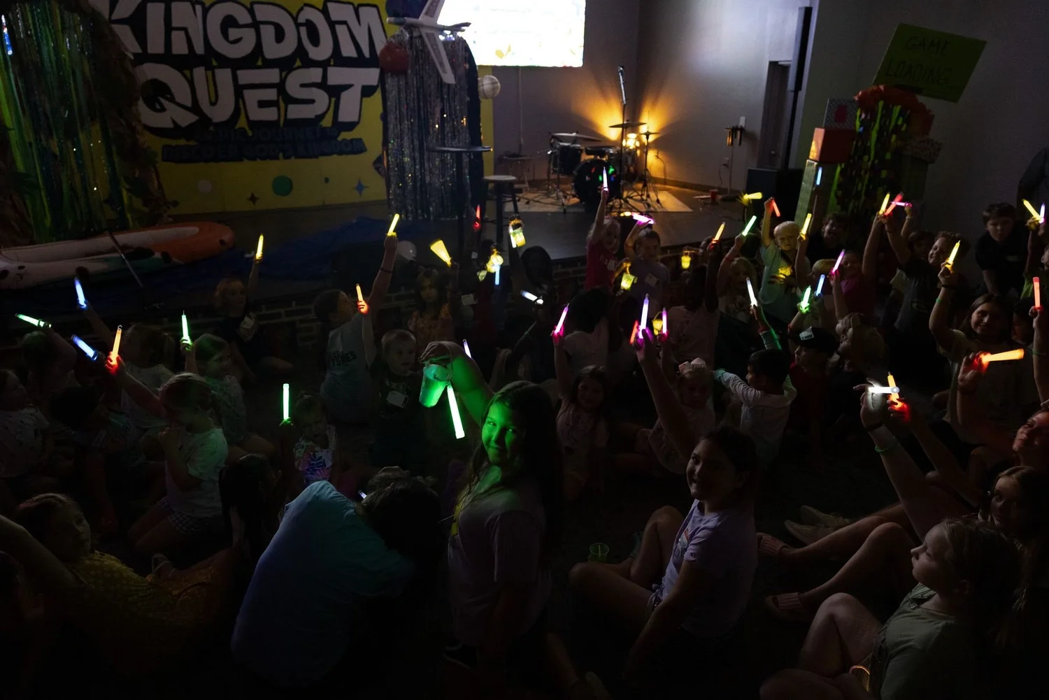 Kids waving glow sticks in a dark room