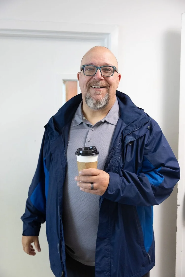 A man smiling with a cup of coffee