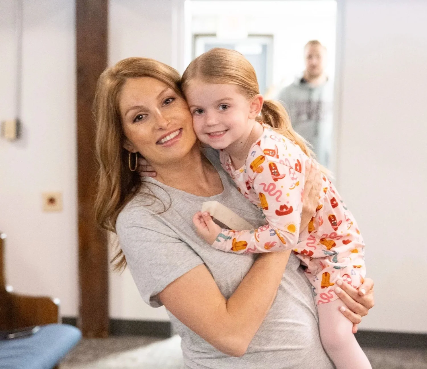 A mom holding her smiling daughter