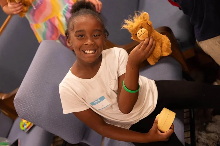 A girl laughing and holding a toy lion