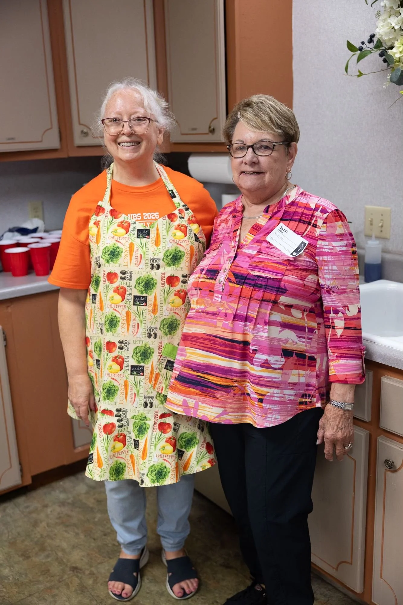 Two volunteers from the kitchen team in aprons