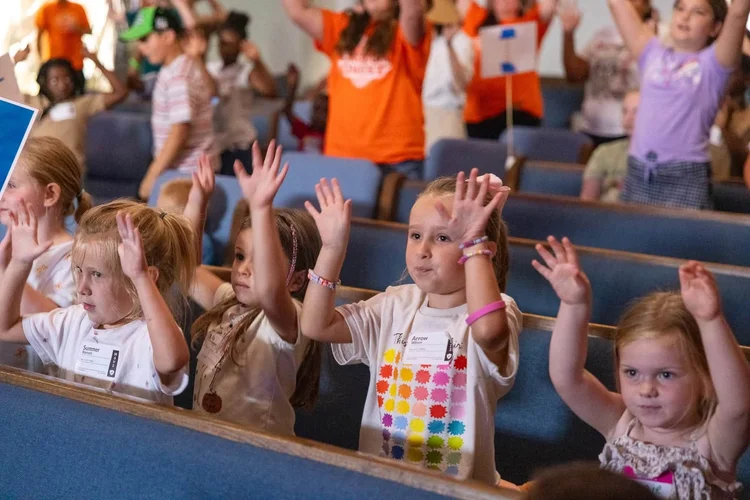 Kids raising their hands at VBS
