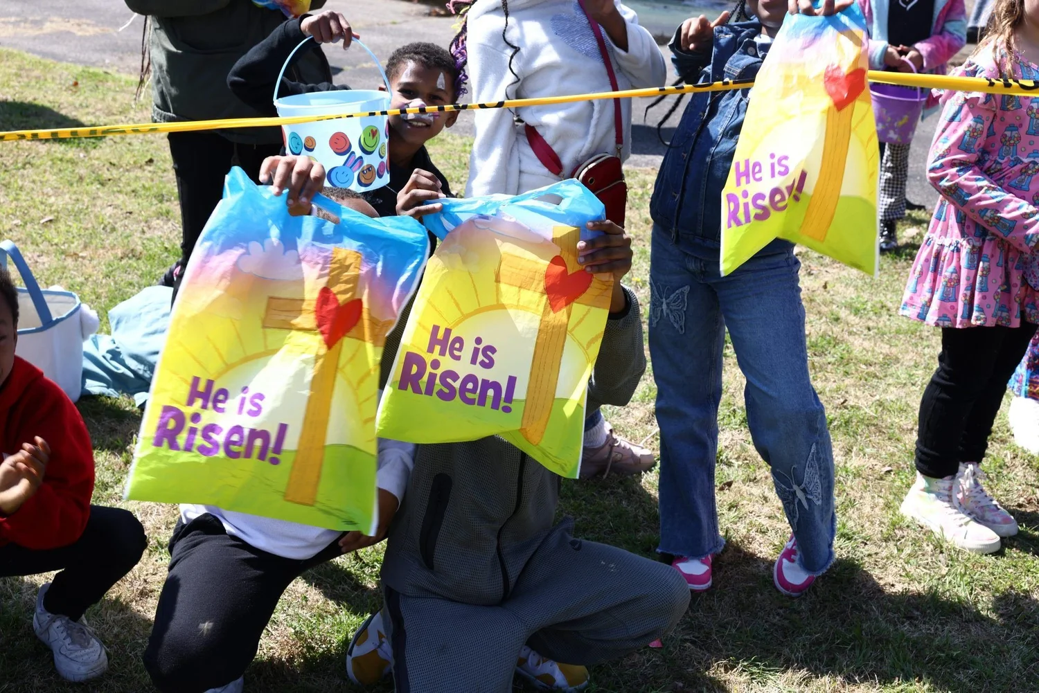 Kids holding He Is Risen bags