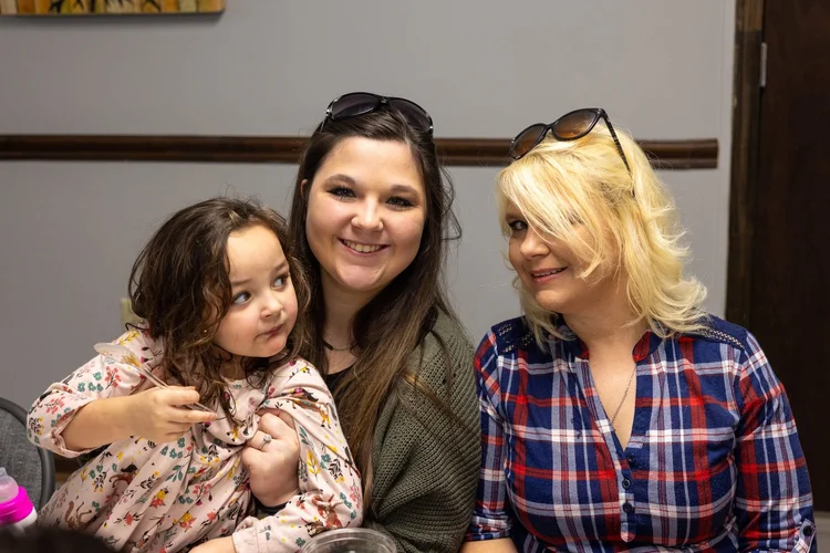 A mom, her daughter and a friend smiling