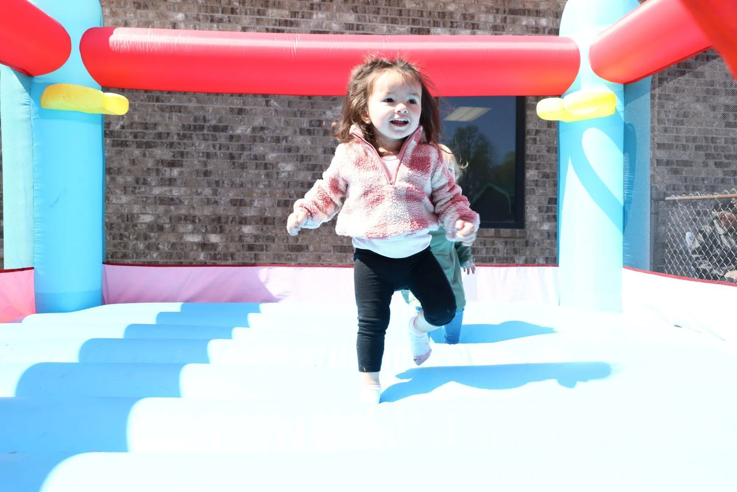 A toddler running in a bounce house