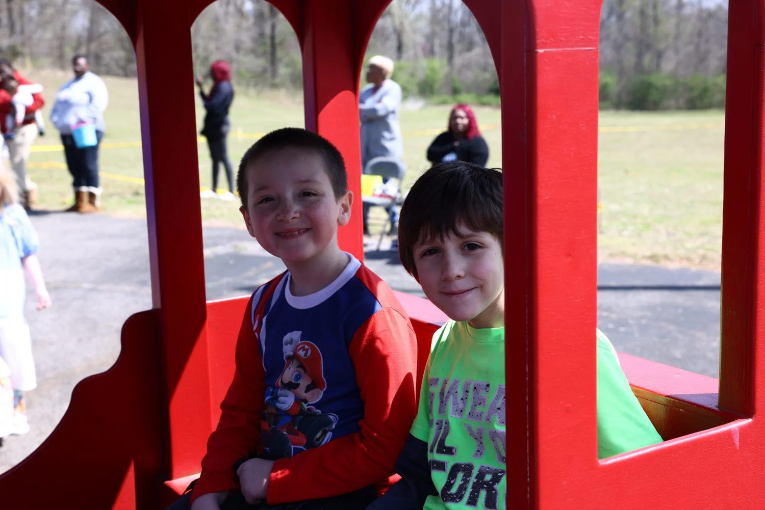 Two boys grinning from a toy train