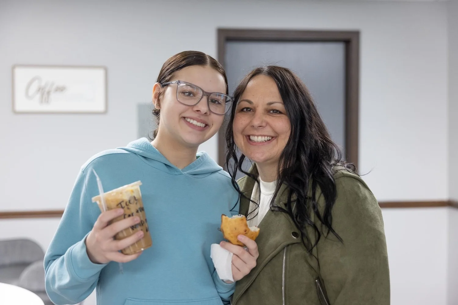 A mother and teenage daughter laughing in the lobby with coffee