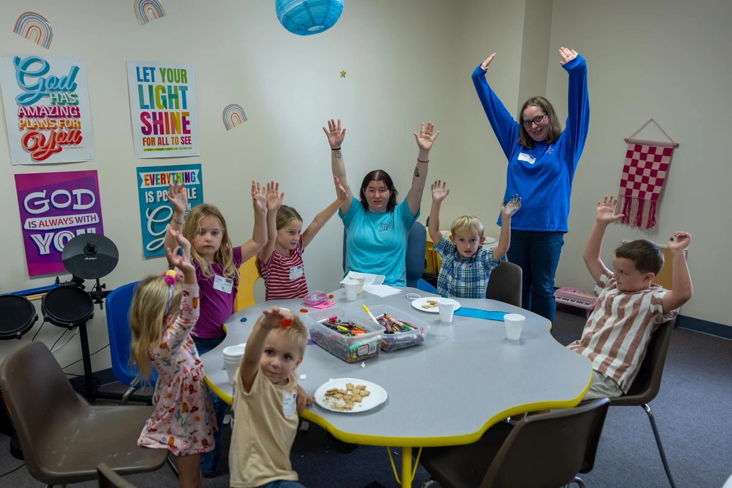 Kids and leaders raising their hands in a Faith Kids room
