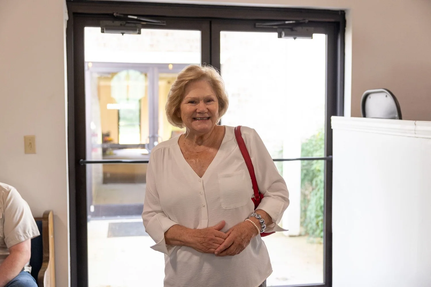 A smiling woman at the front doors of the church