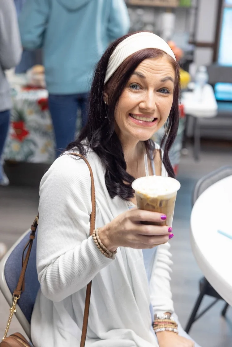 A woman laughing with a coffee in hand