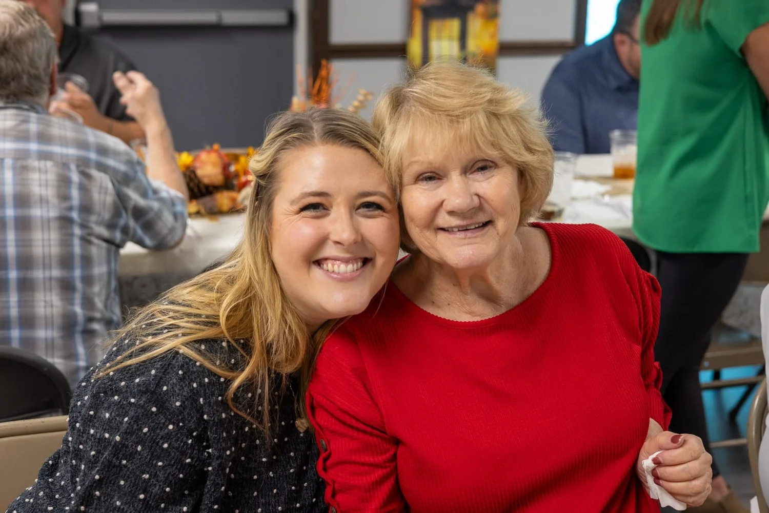 Two women hugging and smiling at a church dinner