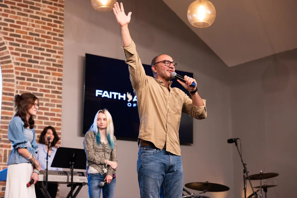 A worship leader singing with his hand raised on Sunday