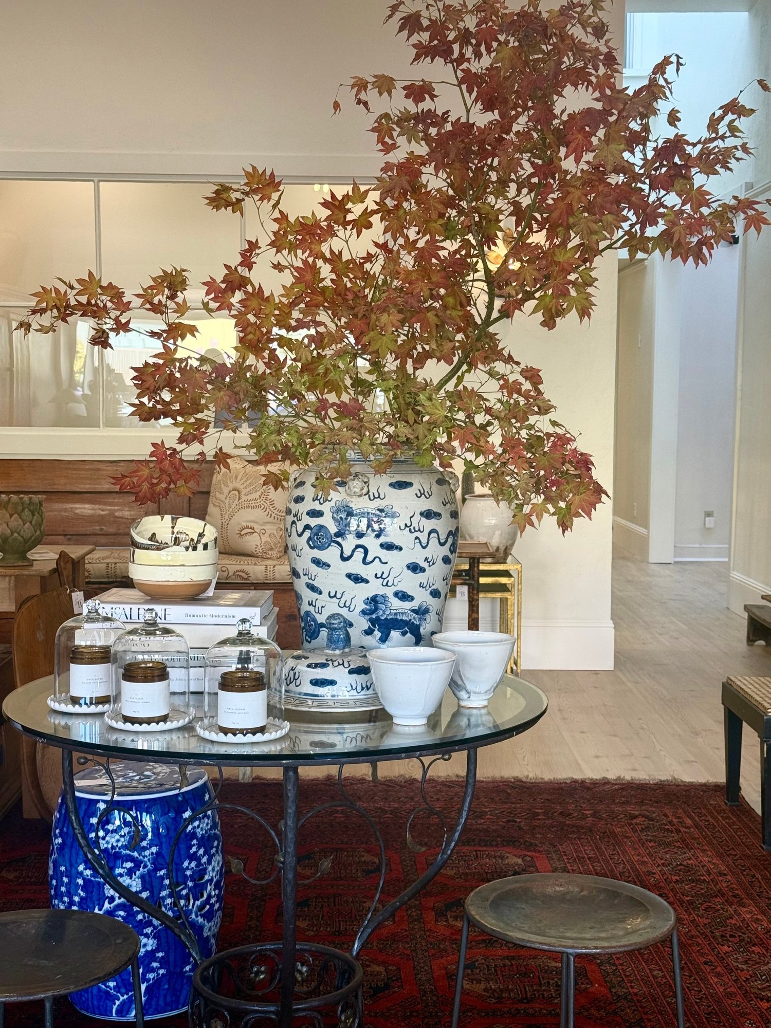 Tama Bell Design showroom with round glass table and autumn maple branches
